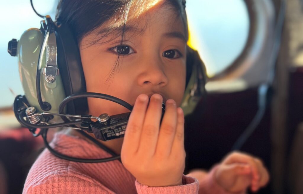 A child on a seaplane tour wearing headphones